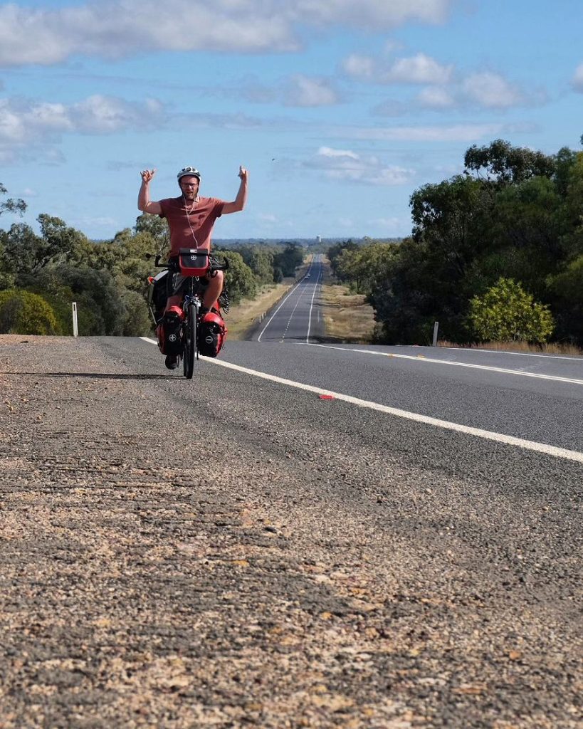 À vélo bras levés sur une longue route
