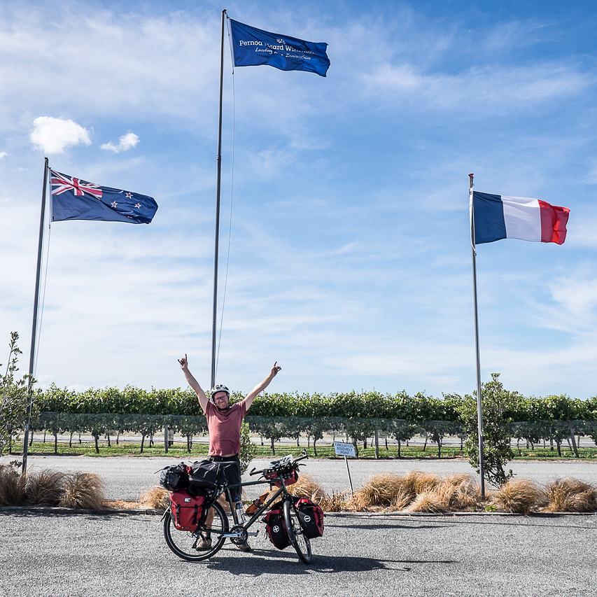 Arrivée à vélo sous les drapeaux, bras levés