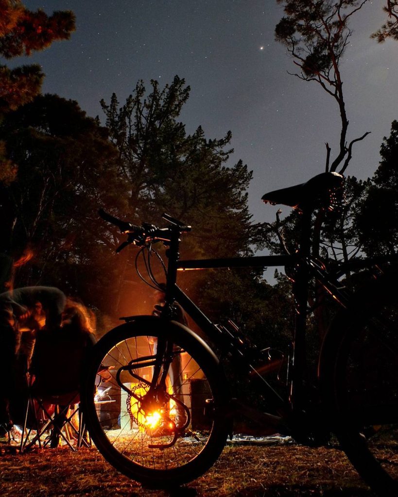 Vélo chargé devant un feu de camp, bivouac