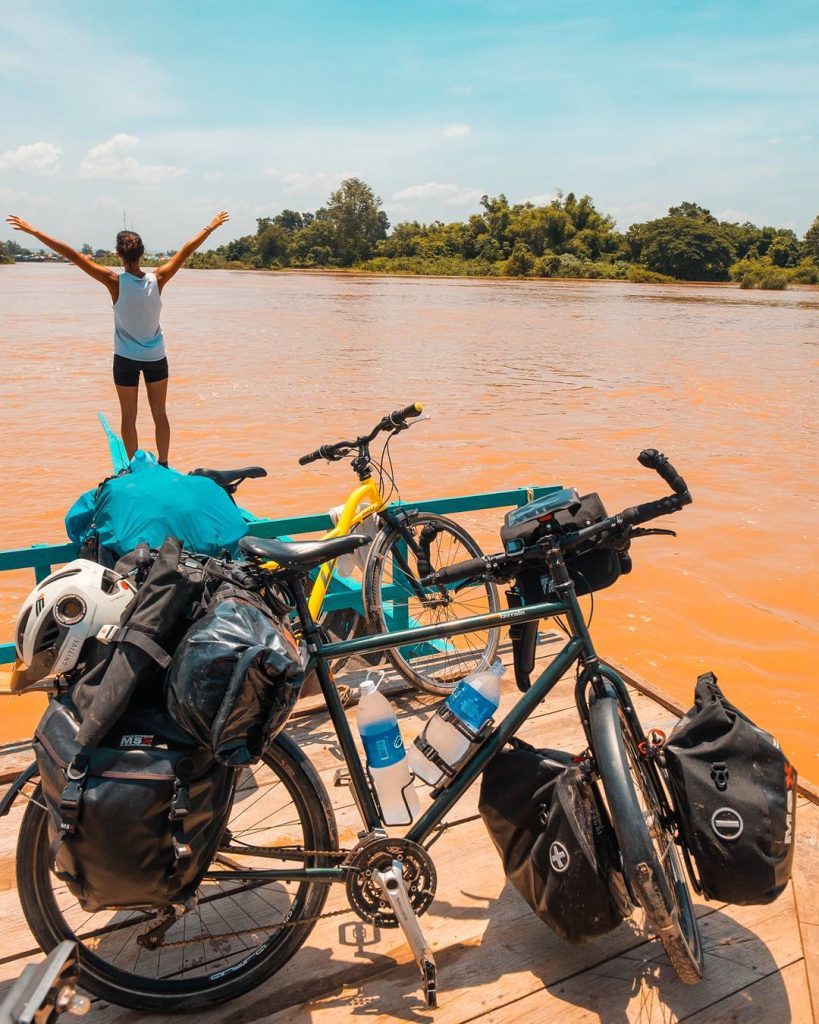 Vélos chargés au bord d'un fleuve, bras levés