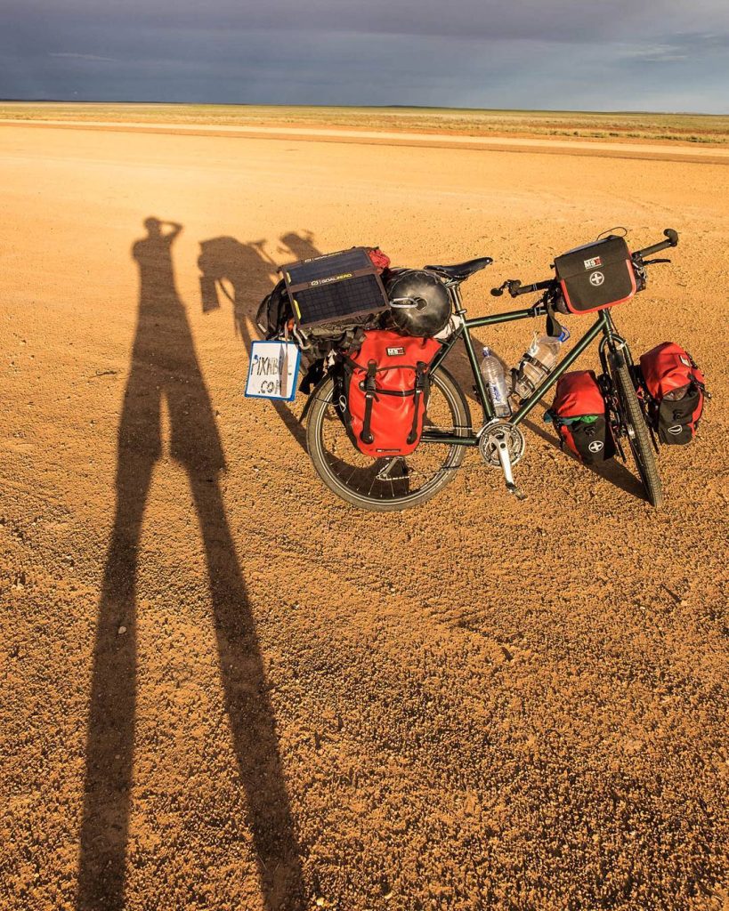 Ombre et vélo chargé sur le sable du désert