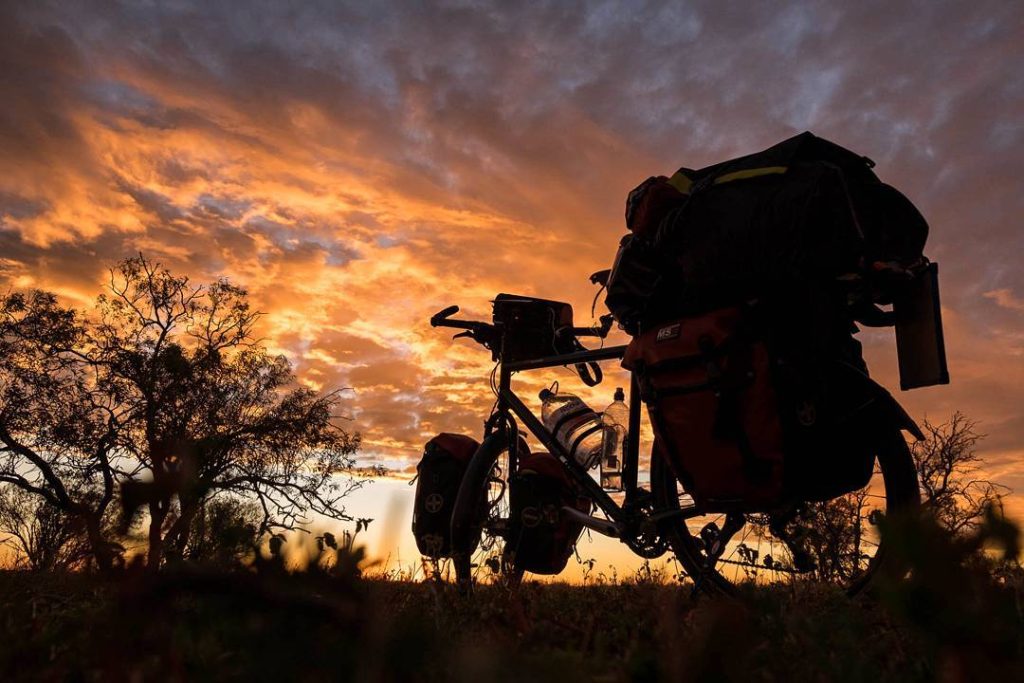 Silhouette d'un vélo chargé au coucher du soleil